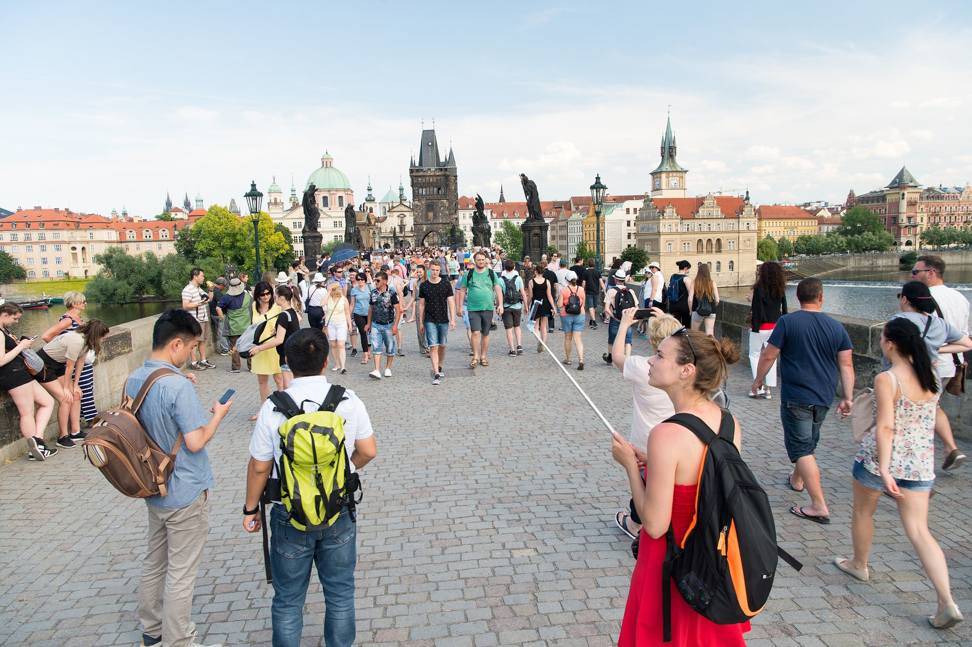 Junge Leute mit Rucksäcken auf der Karlsbrücke in Prag, dahinter der Altstädter Brückenturm
